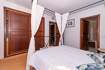 A bedroom with a canopy bed and a picture on the wall