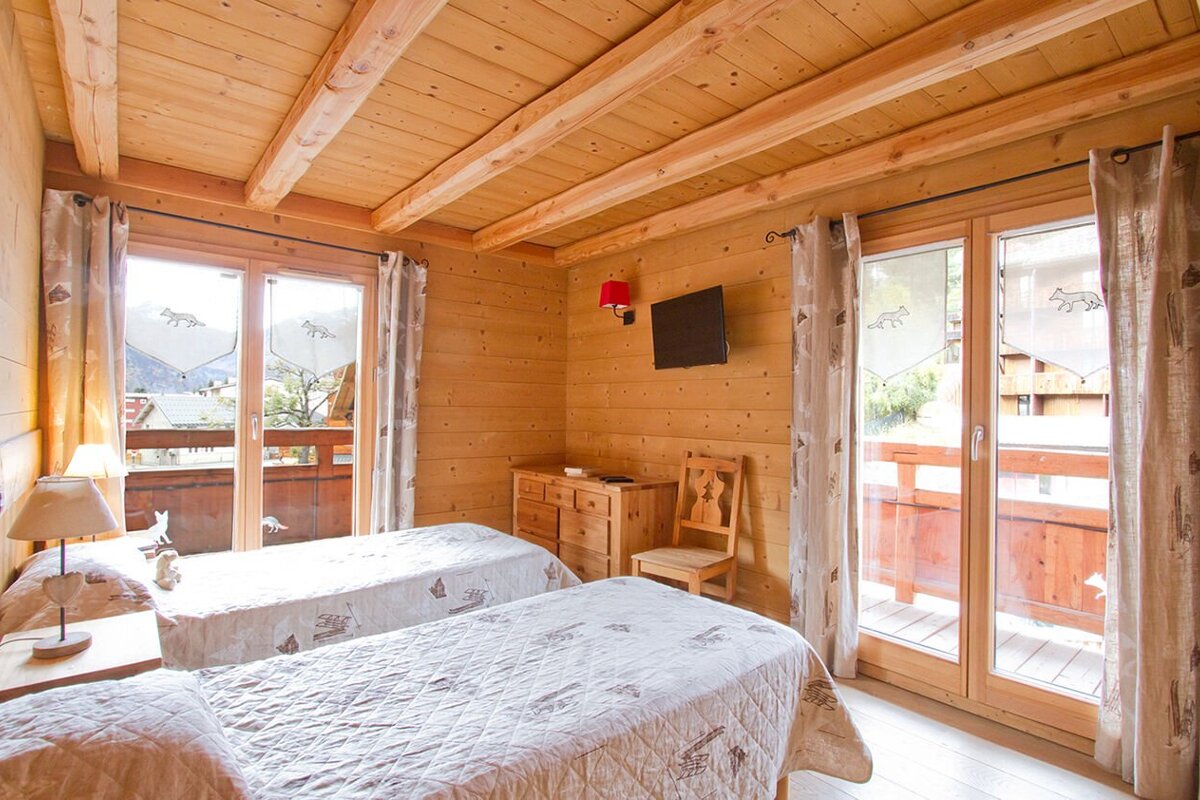 A bedroom with two beds and a television on the wall