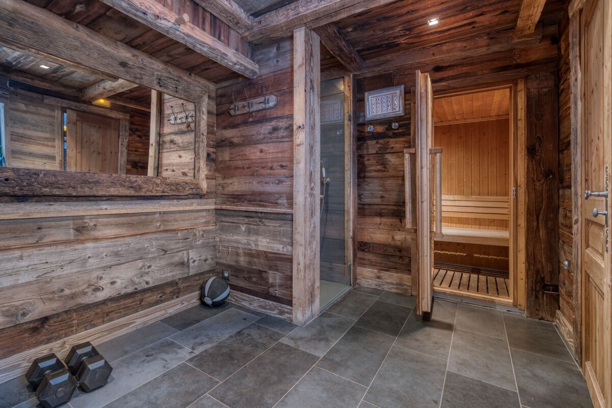 A wooden sauna with a mirror and dumbbells on the floor