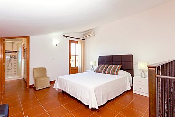 A bedroom with a large bed and a chair