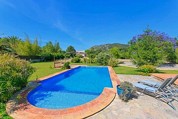 A large swimming pool surrounded by lawn chairs and trees