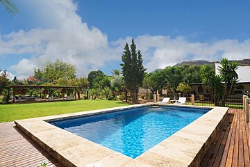 A large swimming pool is surrounded by a wooden deck