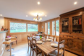A dining room table with a bottle of wine on it