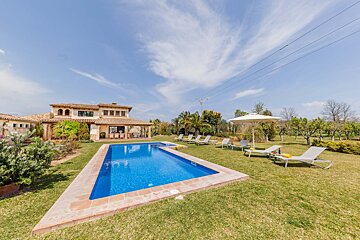 A large swimming pool is surrounded by lawn chairs and umbrellas