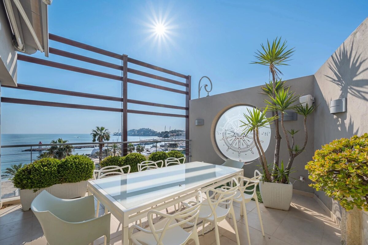 Sun-drenched rooftop terrace with sea and marina views, an outdoor dining table, and a nautical porthole.
