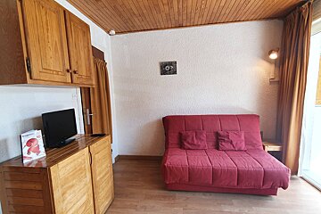 A living room with a red couch and a tv