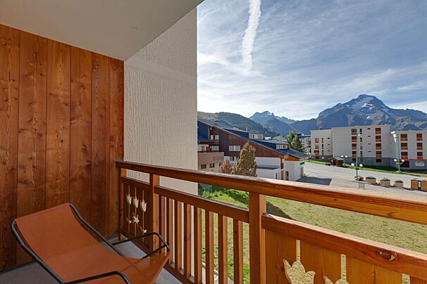 A balcony with a chair and mountains in the background