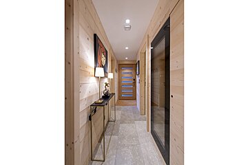 A hallway with wood paneling and a table with a lamp on it