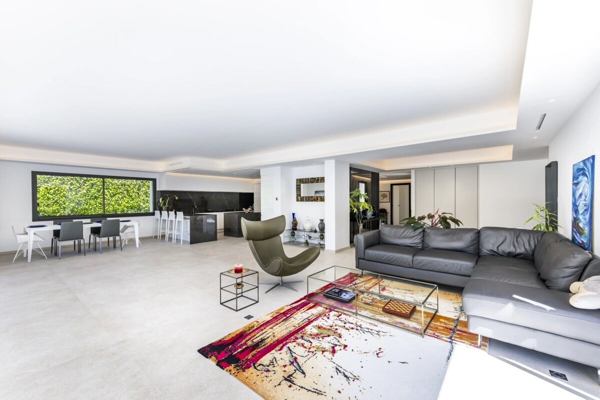 A spacious, modern open-plan living room and dining area with sleek furniture and a colorful accent rug.