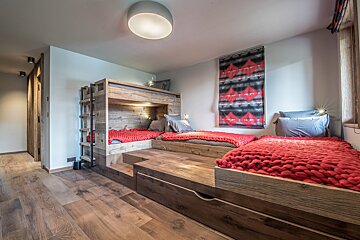 A bedroom with bunk beds and a red blanket
