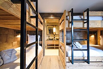 A room with bunk beds and a bathroom with a sink