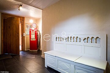 A red gas pump in a hallway next to a white bench
