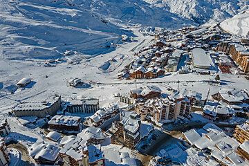 An aerial view of a snowy ski resort with buildings covered in snow