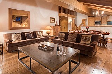 A bottle of wine sits on a wooden table in a living room