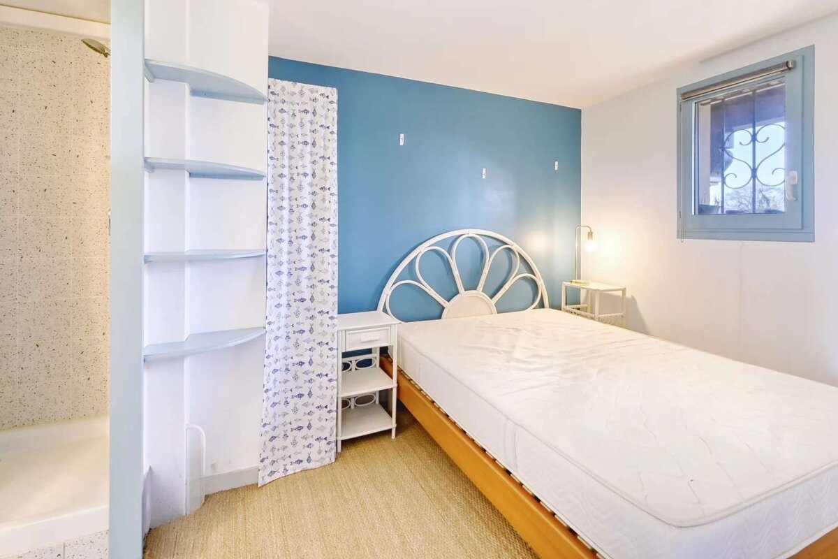 A bedroom with a white mattress and a blue wall