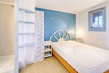 A bedroom with a white mattress and a blue wall