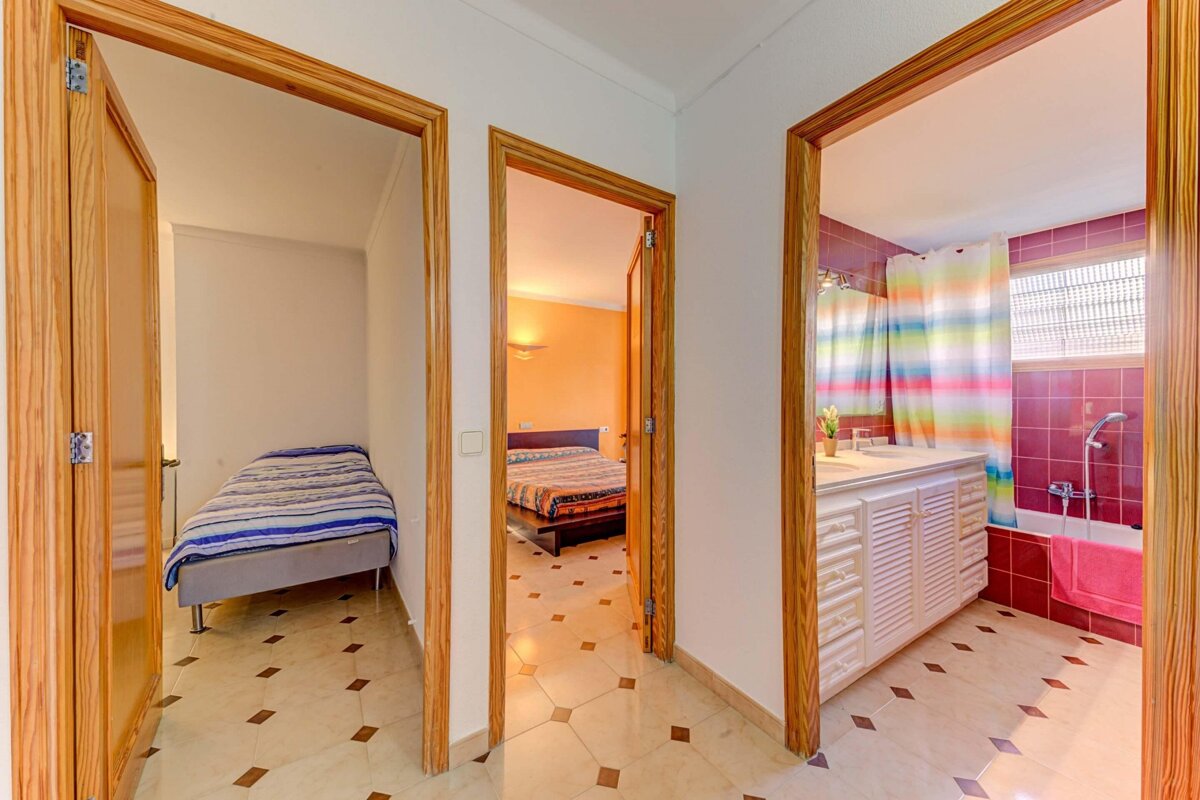 A bedroom with a bed and a bathroom with a rainbow shower curtain