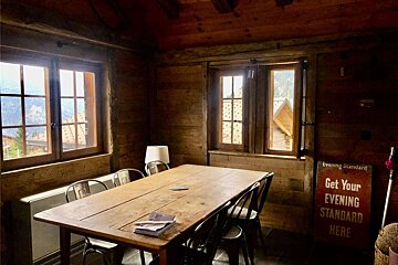 A room with a table and chairs and a sign that says get your evening standard here