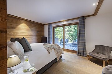 A bedroom with a large bed and a chair