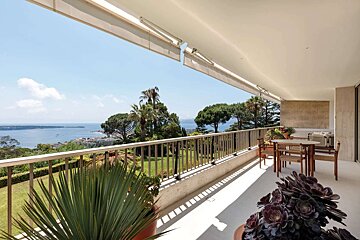 A balcony with a view of the ocean and trees