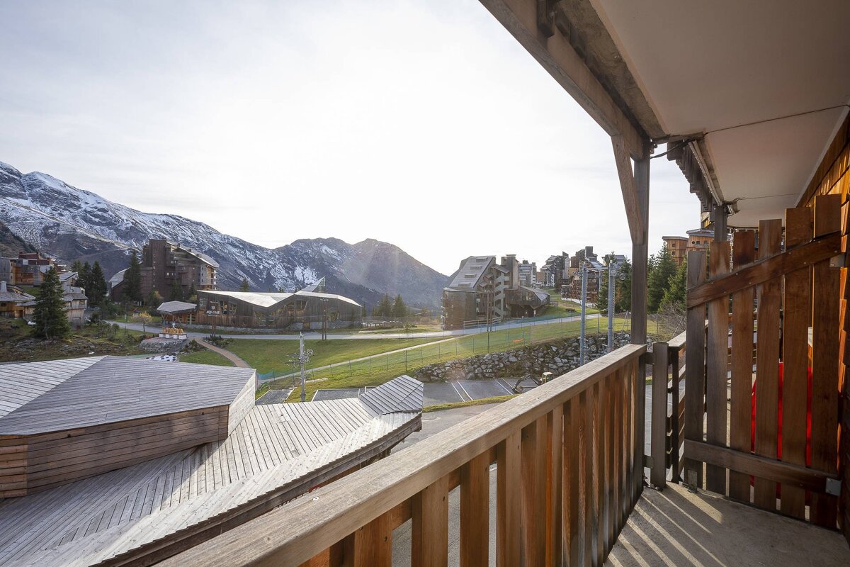 A balcony with a view of a ski resort and mountains