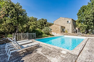 A large stone house with a swimming pool in front of it