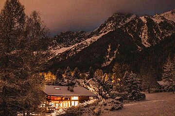 A cabin in the snow with mountains in the background