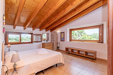 A bedroom with a wooden ceiling and a large window