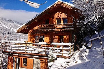 A snowy house with a balcony and a blue sky in the background