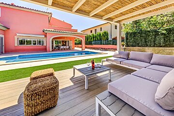 A patio with a couch and a table with a bottle of wine on it