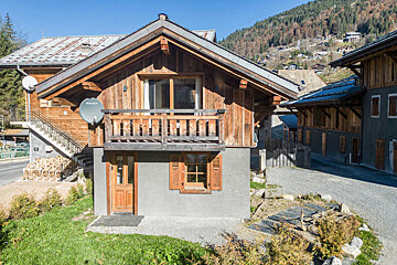 A small house with a balcony sits in the snow