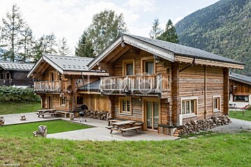 A row of log cabins with a roof that has shingles on it