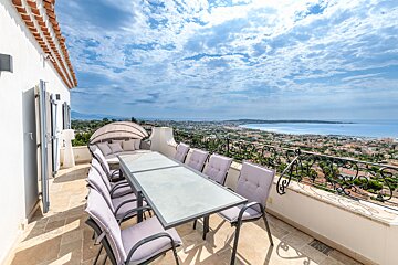 A table and chairs on a balcony overlooking the ocean