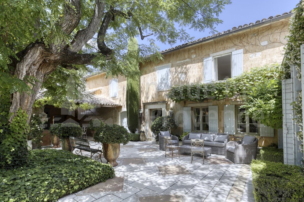 A patio with a couch and chairs in front of a house