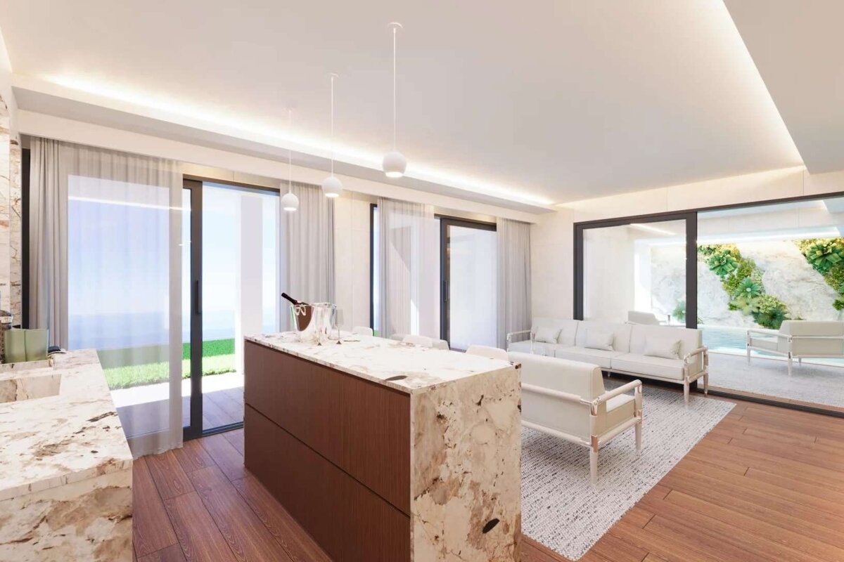 A luxurious, bright open-plan living area featuring a sleek island, white sofas, warm wooden floors, and large glass doors connecting to green outdoor spaces.