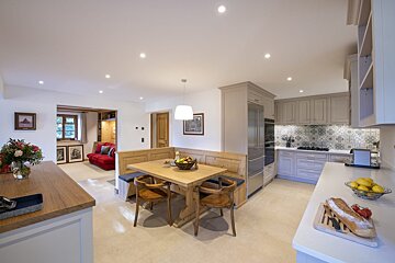 A kitchen with a table and chairs and a bowl of fruit