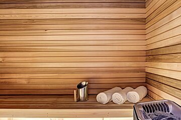 A wooden sauna with towels and a bucket on the shelf