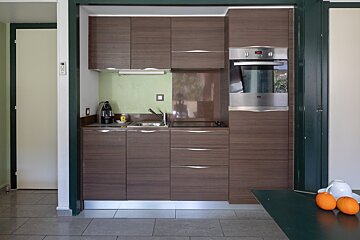 A small kitchen with wooden cabinets and a stainless steel oven