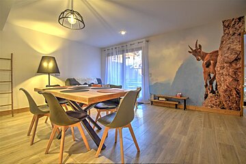 A room with a table and chairs and a picture of a goat on the wall