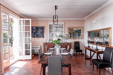 A dining room with a large wooden table and chairs