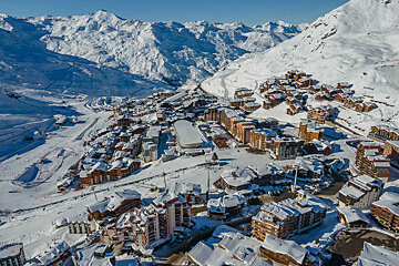An aerial view of a snowy ski resort with mountains in the background