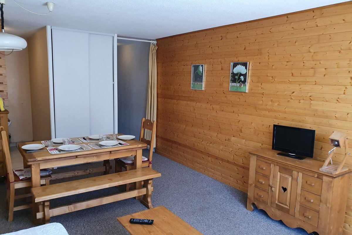 A living room with a table and chairs and a flat screen tv