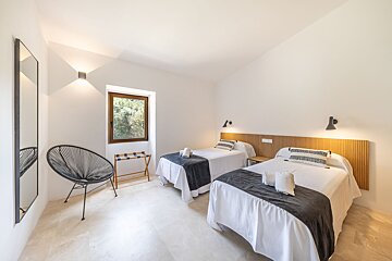 A bedroom with two twin beds and a chair