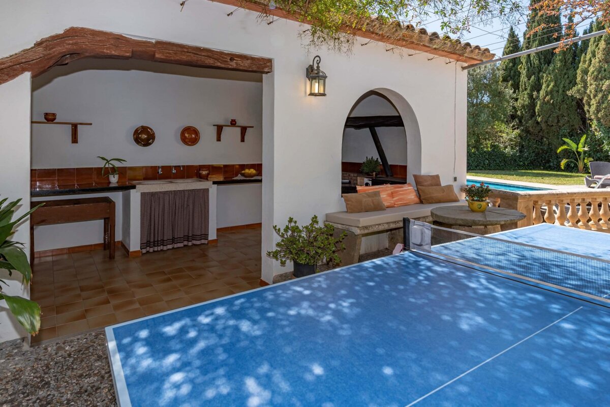 A blue ping pong table sits outside of a house
