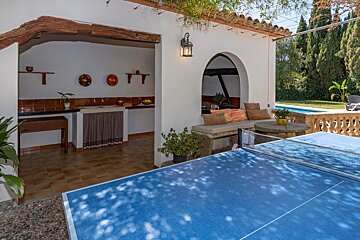 A blue ping pong table sits outside of a house