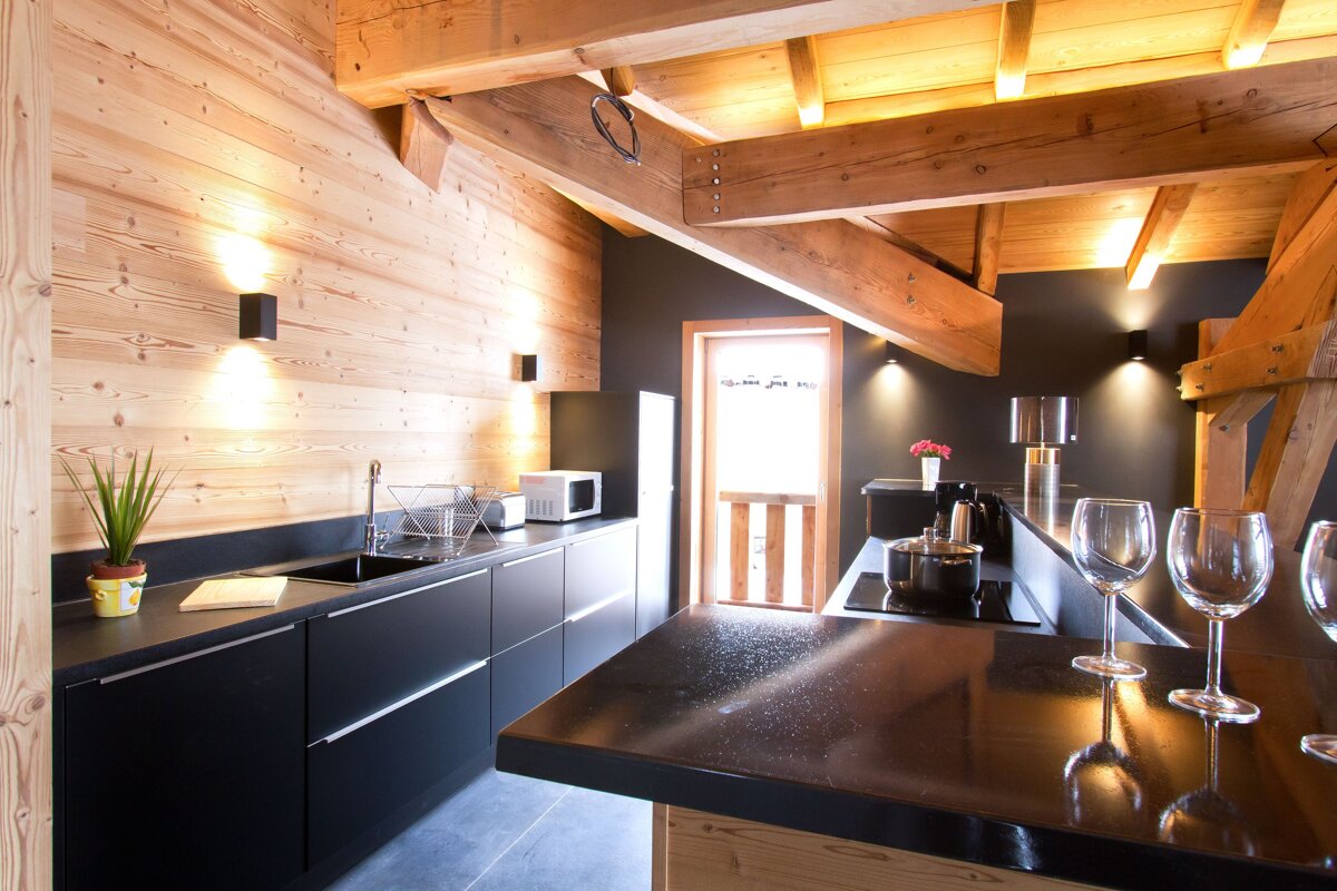 A kitchen with a black counter top and wooden walls