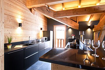 A kitchen with a black counter top and wooden walls