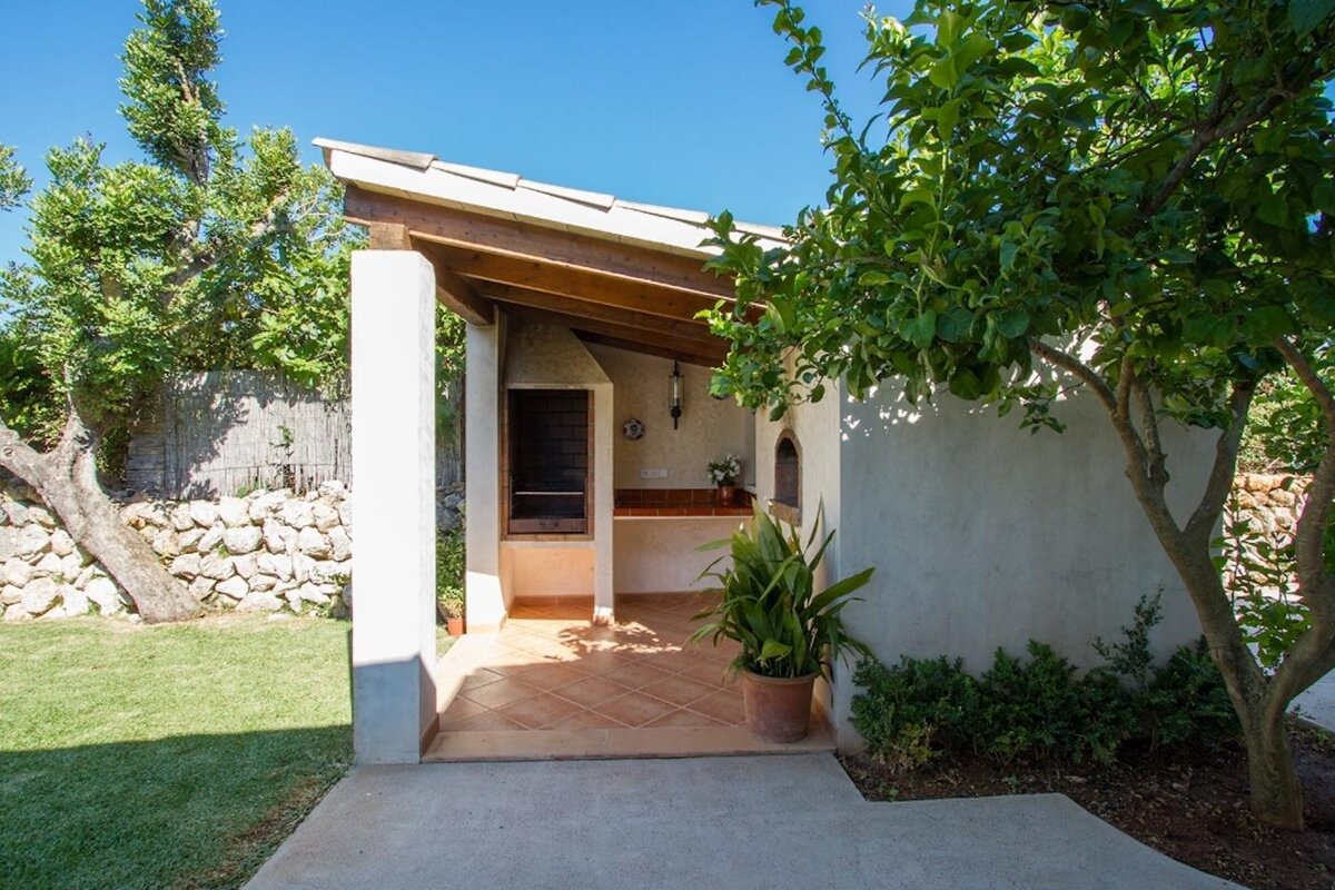 A stone house sits in the middle of a lush green field
