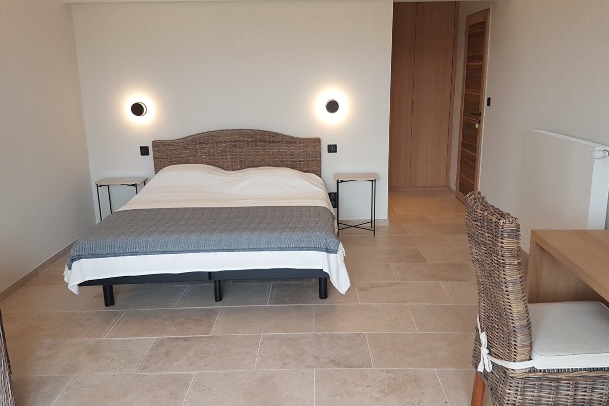 A bedroom with a large bed and wicker chairs