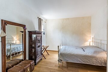 A bedroom with a bed and trunks and a mirror